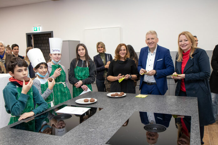 In der neuen Schullehrküche wurde auch das Schülerprojekt „Gesunde Ernährung“ vorgestellt – und es gab viele Leckereien zum Probieren. Auf dem Bild im Vordergrund von links: Manuel Messina (6a), Esma Gezginci (6c), Jenny Joy Kaiser (7a) und Roda Haji (6a) mit Schulleiterin Ute Strozynski, Landrat Patrik Lauer und Bildungsministerin Christine Streichert-Clivot. Foto: Landkreis Saarlouis/Ulrike Paulmann