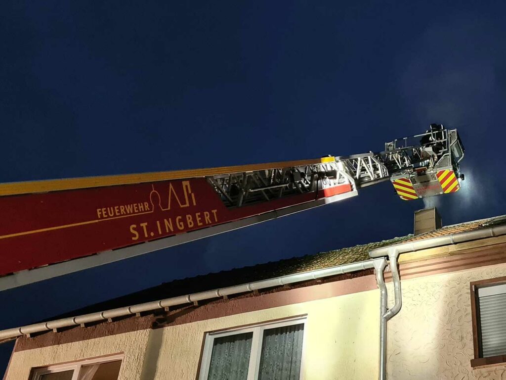 Der Kamin wird durch eine Feuerwehrmann mit Atemschutz aus dem Korb der Drehleiter gekehrt, Bild: Markus Zintel/Feuerwehr