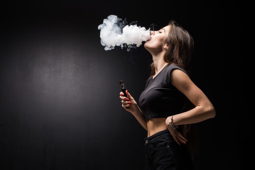 Vaping vor oder nach dem Training: eine wachsende Debatte unter Sporttreibenden. Fotoquelle: https://www.freepik.com/free-photo/young-beautiful-brunette-woman-smoking-vaping-e-cigarette-with-smoke-black-wall_9314174.htm#page=2&query=vaping&position=1&from_view=keyword&track=sph&uuid=4089c04f-c871-448b-b149-8bb8dcc9bd8c