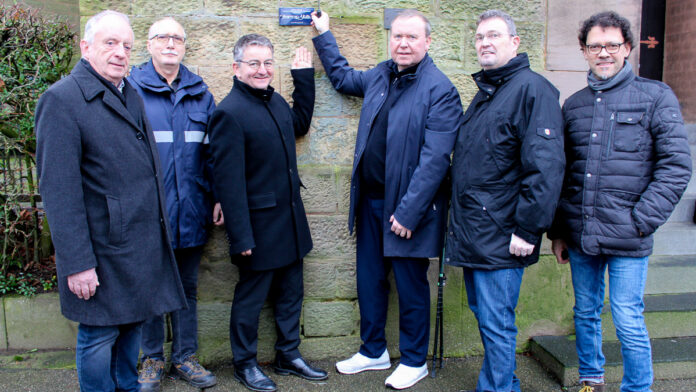 (v.l.) Presbyter Günther Kliebenstein, Küster Alexander Bengraf und Pfarrer Heiko Poersch von der Kirchengemeinde Dudweiler/Herrensohr mit Stefan Pauluhn (Saartoto), Ralf-Peter Fritz (Bezirksbürgermeister Dudweiler) und Markus Braun (Landesdenkmalamt) beim Anbringen der Plakette neben dem Portal der Christuskirche Foto: evks/Eulenstein